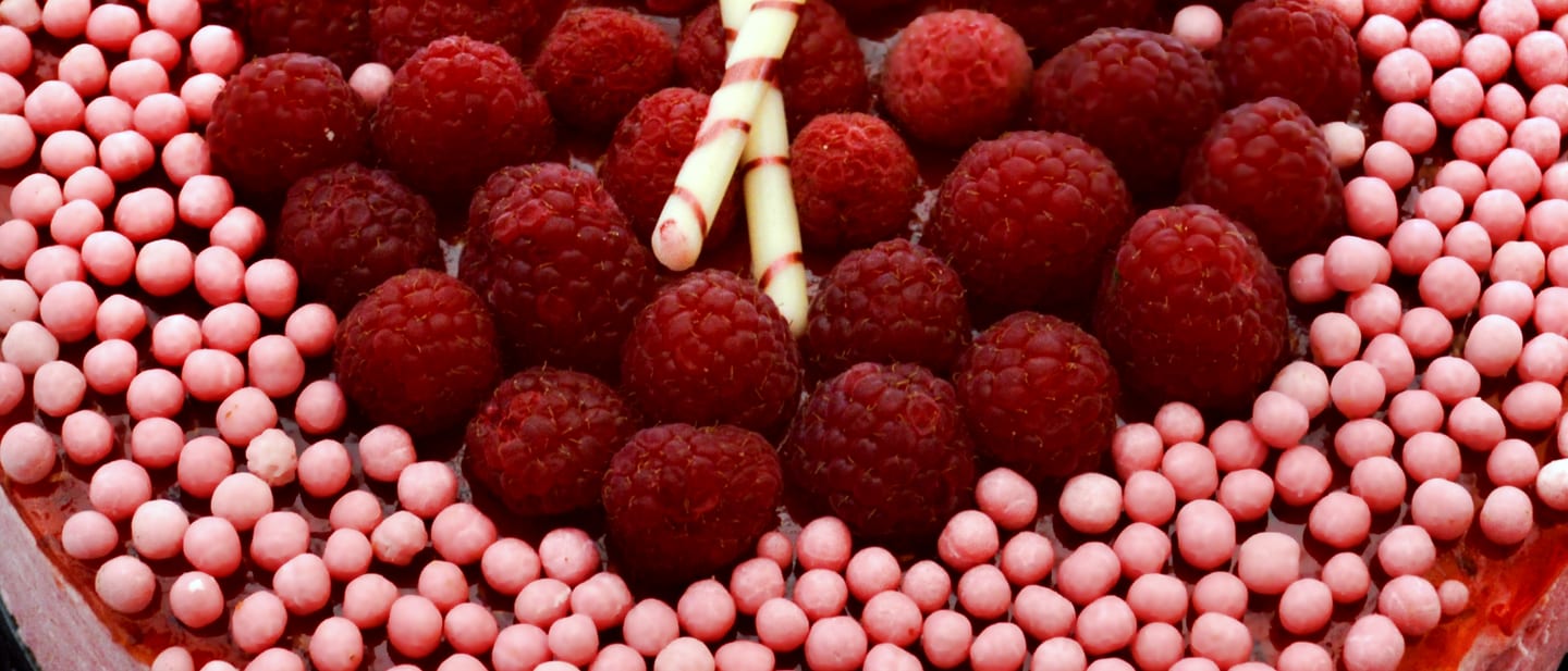Frambuesas y perlas de azúcar rosas cubriendo una mousse, vistas de cerca