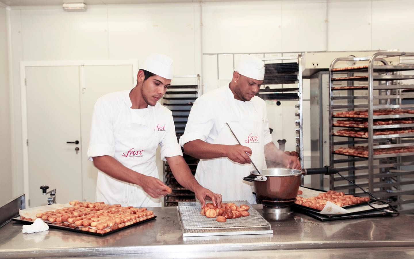 Dos pasteleros de Fast trabajando juntos con palmeritas en el obrador