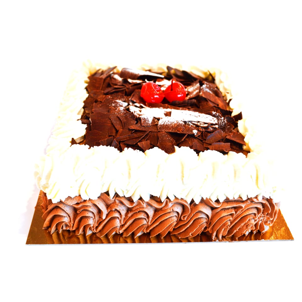 Tarta Selva Negra entera, cuadrada, con virutas de chocolate negro por encima y cordones de nata y trufa en el lateral